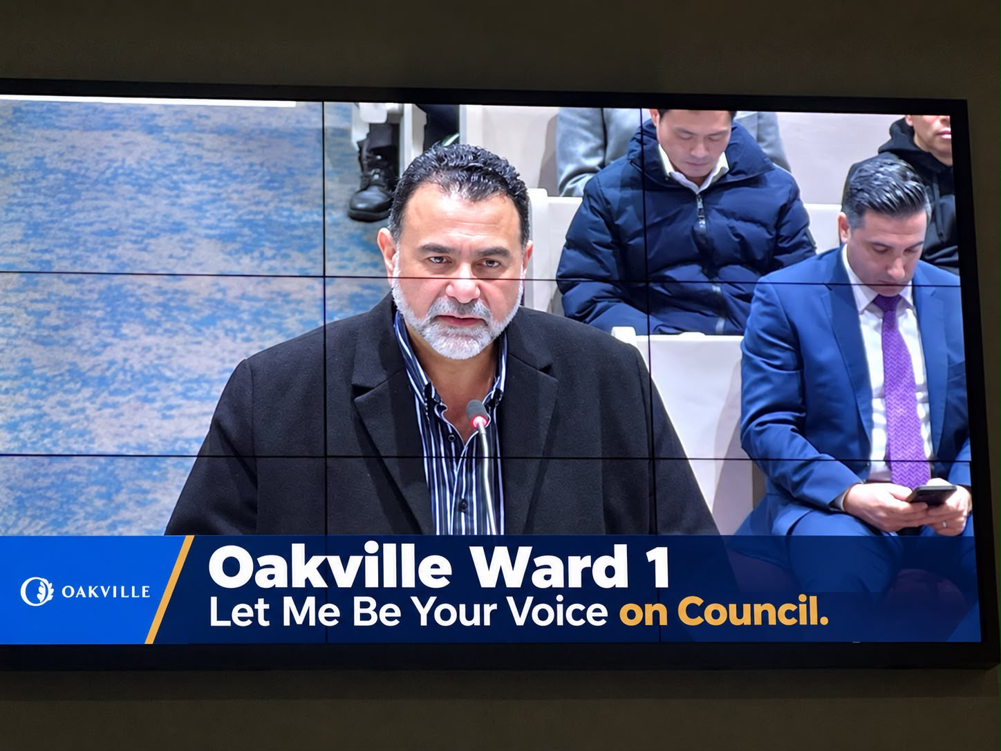 Amir Henry speaking at a town hall meeting on the broadcast screen